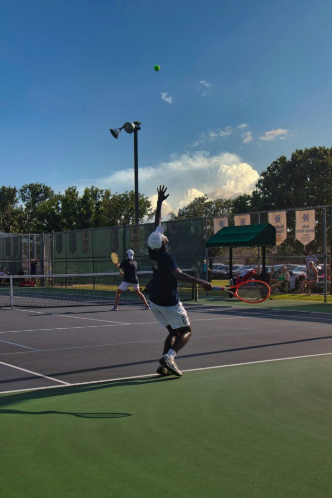 A tennis player hitting a serve during a doubles match